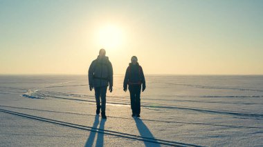 The two expeditors with backpacks walking through the snow field