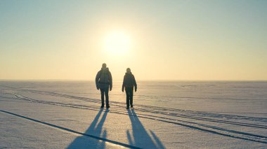 The two expeditors with backpacks walking through the snow field