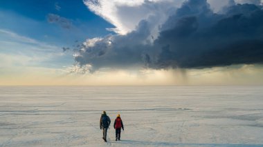 The two people walking through the endless snow field