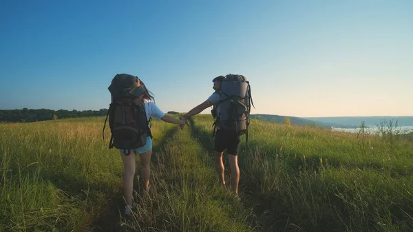 The man and woman walking with backpacks on a blue sky background