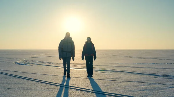 The two expeditors with backpacks walking through the snow field