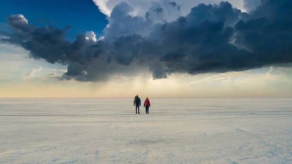 The two people walking through the endless snow field
