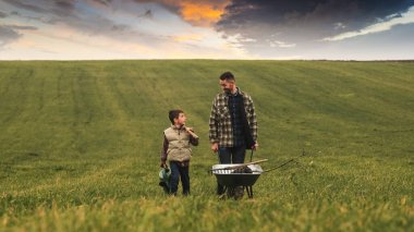 The dad and son walking through the field on a beautiful sky background