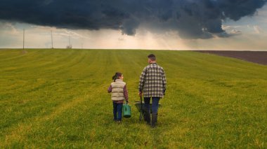 The farmer with his little son walking through the green field