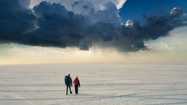 The two backpackers walking through the icy snow field