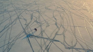 The upper view on a travelers going through the snow field