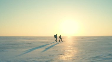 The two people with backpacks going through the snow field