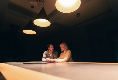 The young couple sitting at the table in empty night bar