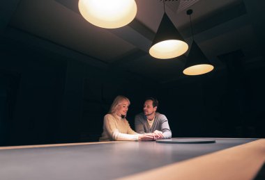 The young couple sitting at the table in empty night bar