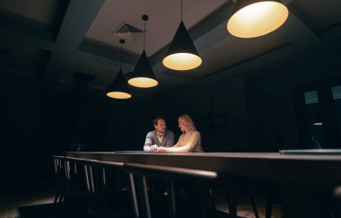 The romantic couple sitting at the table in empty night restaurant