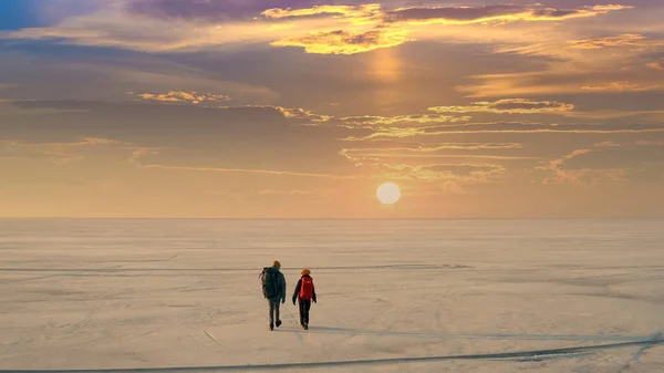 The two people with backpacks going through the snow field