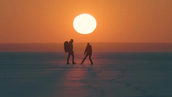 Two Travelers Walking Arctic Snowy Field Sunset Background – stockfoto