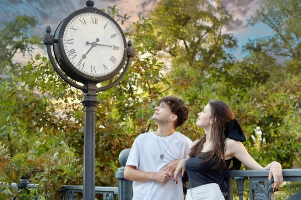 一个年轻人和一个女孩正在看一个安装在街上的大钟 — 图库照片