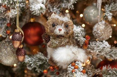 Şişmiş sincap şeklinde bir Noel oyuncağı süslenmiş bir Noel ağacına asılır..