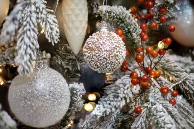 Noel oyuncakları karla kaplı bir Noel ağacında asılı duruyor.