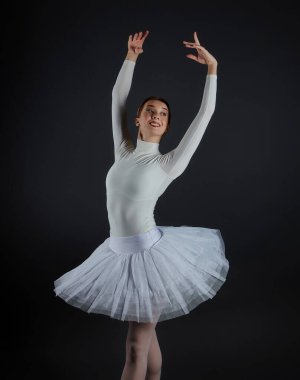 Stüdyoda karanlık arka planda poz veren zarif bir balerin..