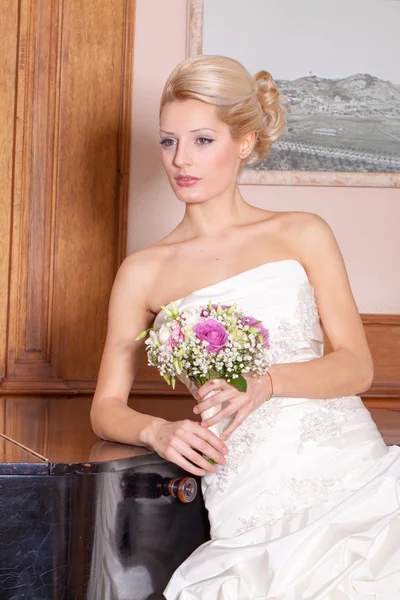 Bride with beautiful smile and blonde hair next to piano. — Stock Photo, Image