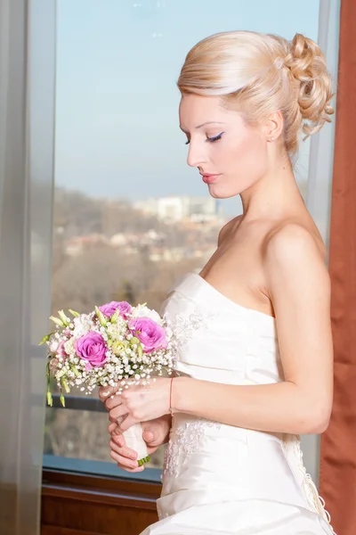 Belle mariée blonde regardant son bouquet de mariage . — Photo