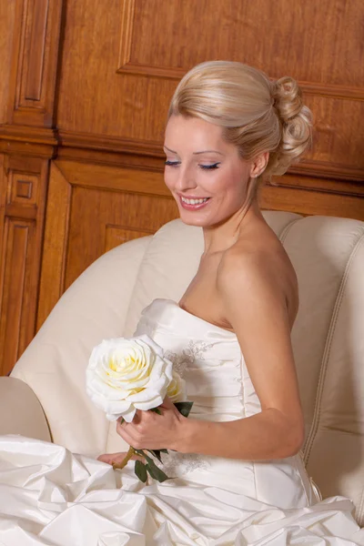 Portrait of beautiful bride with blond hair sitting on a sofa. — Stock Photo, Image