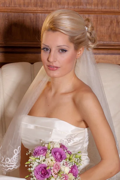 Beautiful blonde bride sitting on a sofa — Stock Photo, Image
