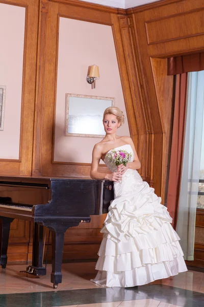 Bride with beautiful smile and blonde hair next to piano. — Stock Photo, Image