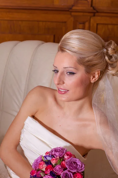 Portrait intérieur d'une adorable mariée aux cheveux blonds assise sur un canapé . — Photo