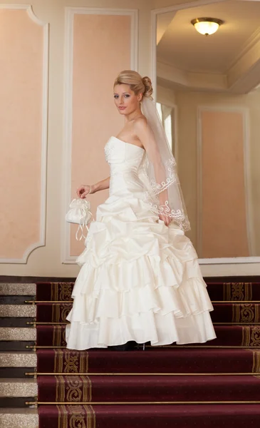 Beautiful blonde bride standing on the stairs. — Stock Photo, Image