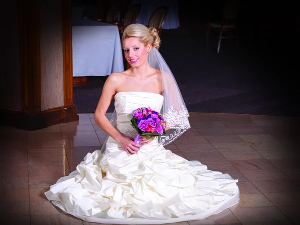 Mooie blonde bruid zittend op de vloer — Stockfoto