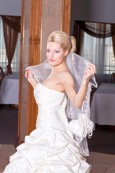 Schattige blonde bruid met elegante bruiloft jurk en sluier. — Stockfoto