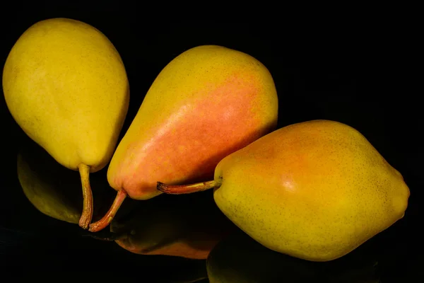 Reife gelbe Birnenfrucht, mit Reflexion in schwarzer Oberfläche, isoliert auf schwarz — Stockfoto