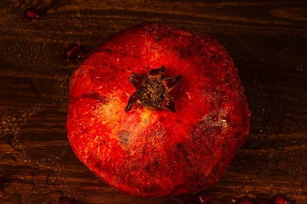 Red ripe wet pomegranate on the table. Close-up — Stock Photo, Image