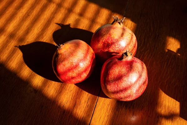Three ripe pomegranates on the wooden table — Stock Photo, Image
