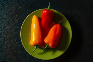 Yeşil bir tabakta üç olgun tatlı biber, yakın plan..