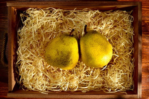 木のテーブルの上にシェービング付きの箱の中に2本の熟した梨 クローズアップ トップビュー — ストック写真
