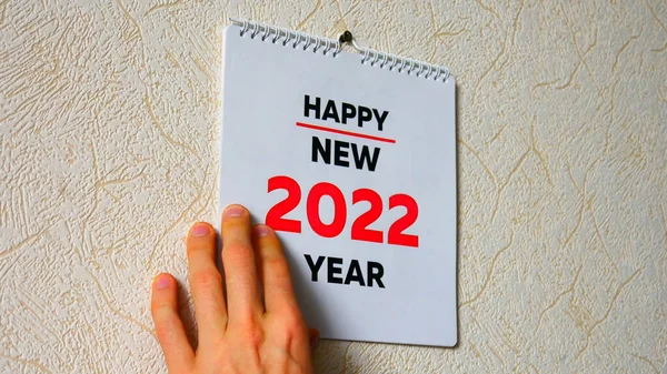Duvarda asılı olan 2022 takviminin başlık sayfasının kapağı ve üzerinde bir erkek eli