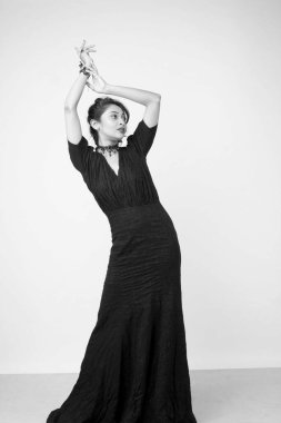 Stüdyoda sağlam bir arkaplan önünde şık siyah elbiseli güzel bir kadın manken.