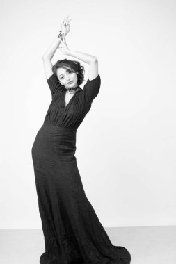 Stüdyoda sağlam bir arkaplan önünde şık siyah elbiseli güzel bir kadın manken.