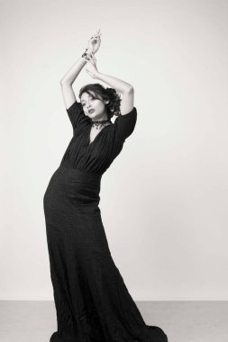 Stüdyoda sağlam bir arkaplan önünde şık siyah elbiseli güzel bir kadın manken.