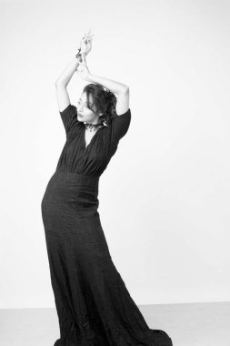 Stüdyoda sağlam bir arkaplan önünde şık siyah elbiseli güzel bir kadın manken.