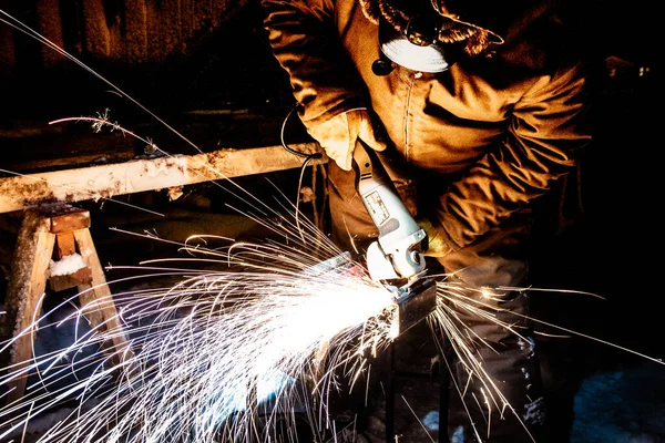 Worker grinding metal in the winter and in the dark