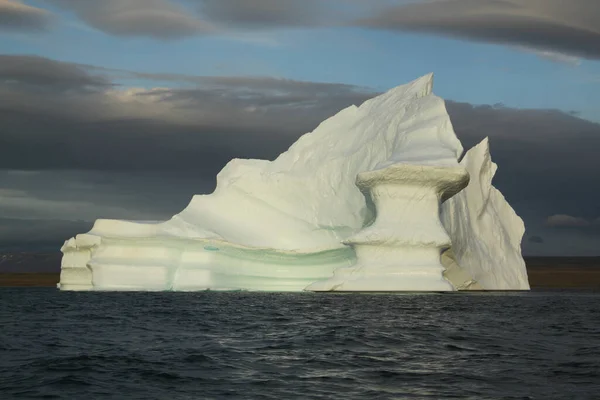 Kuzey Kutbu 'ndaki Pond Inlet, Nunavut, Kanada yakınlarında akşam üzeri karaya oturmuş buzdağı ve buz tabakası