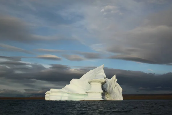 Kuzey Kutbu 'ndaki Pond Inlet, Nunavut, Kanada yakınlarında akşam üzeri karaya oturmuş buzdağı ve buz tabakası