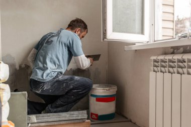 Avrupalı görünümlü bir adam duvarları kaplıyor, daireyi onarıyor, evi onarıp yeniden dekore ediyor.