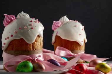 Paskalya pastaları, geleneksel renkli yumurtalar şenlik masasında, koyu arkaplanda.