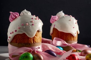 Paskalya pastaları, geleneksel renkli yumurtalar şenlik masasında, koyu arkaplanda.