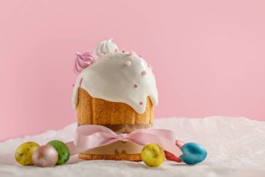 Paskalya pastaları, geleneksel renkli yumurtalar şenlik masasında, pembe arka planda.