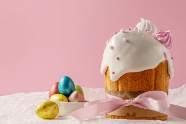 Paskalya pastaları, geleneksel renkli yumurtalar şenlik masasında, pembe arka planda.
