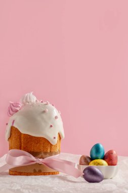 Paskalya pastaları, geleneksel renkli yumurtalar şenlik masasında, pembe arka planda.