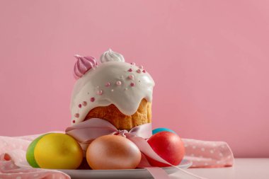 Paskalya pastaları, geleneksel renkli yumurtalar şenlik masasında, pembe arka planda.
