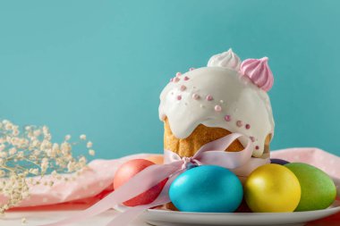 Paskalya pastaları, geleneksel renkli yumurtalar şenlik masasında, mavi arka planda.